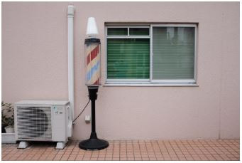 Air conditioner unit in front of shop on the left side of the window.