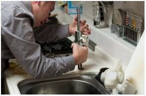 Man installing sink faucet in kitchen