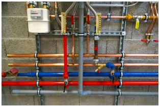 Piping assembly mounted on cement block wall. Copper and steel piping.