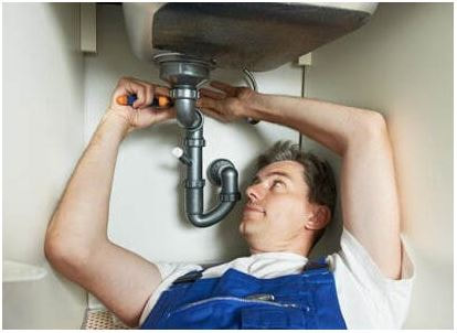 Man fixing sink while laying underneath it with his wrench.